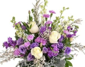 White roses are set off by a mix of purple, lavender, pink and fragrant flowers. Depending on seasonal availability this bouquet may include