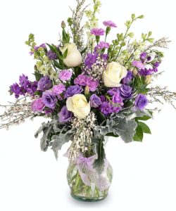 White roses are set off by a mix of purple, lavender, pink and fragrant flowers. Depending on seasonal availability this bouquet may include lisianthus mini carnations stock genista dusty miller delphinium larkspur