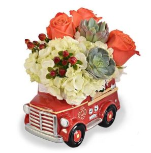 Ceramic fire truck approximately 5" wide by 7" long loaded with white HYDRANGEAS, ROSES, HYPERICUM and SUCCULENTS. Any Dad would love this RED HOT planter on his desk. Local metro St Louis area delivery only!