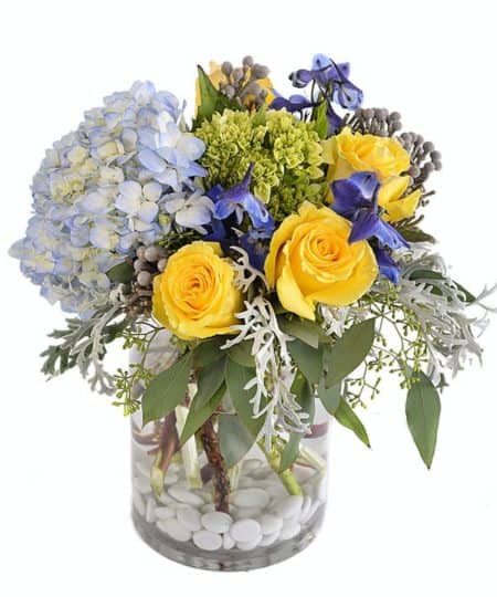 This "all around" display of roses, hydrangea, berzelia balls, larkspur, seeded eucalyptus and river rocks will even impress Mother Nature! approx 11" tall by 10" wide -