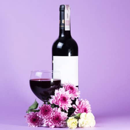 Red wine bottle on the purple background with spring flowers