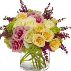 medley of roses in gentle hues of pink, peach and white – accented with heather and a touch of green hydrangea